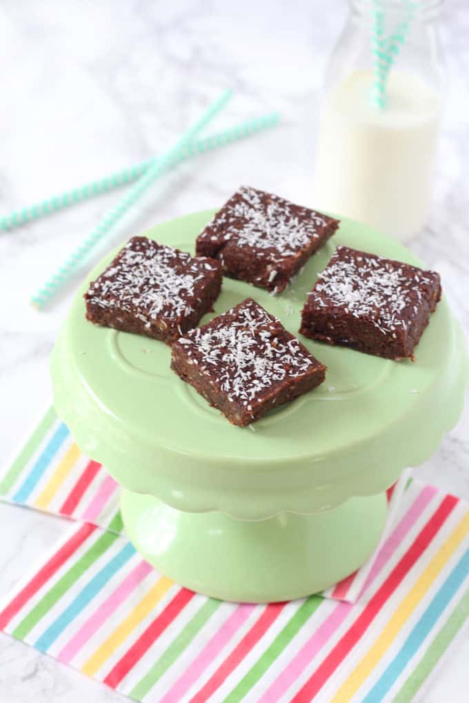 Brownie bites on a light green cake stand with a mini bottle of milk in the background