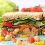 A delicious vegan sandwich packed with spicy sriracha chickpeas, lettuce, spinach, tomatoes and peppers. Perfect for a 2 minute healthy lunch for busy parents!