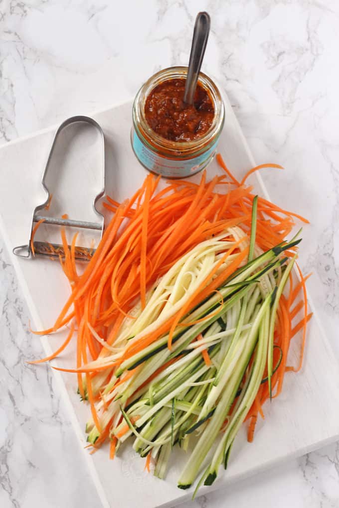 julienne carrots and courgette on a chopping board with a jar of laksa paste 