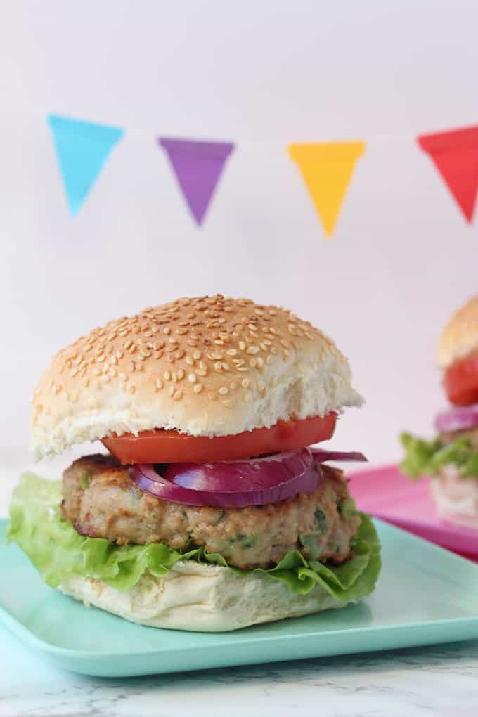 feta & spinach turkey burger in a sesame seed bun with lettuce, onion and tomato on a turquoise plate