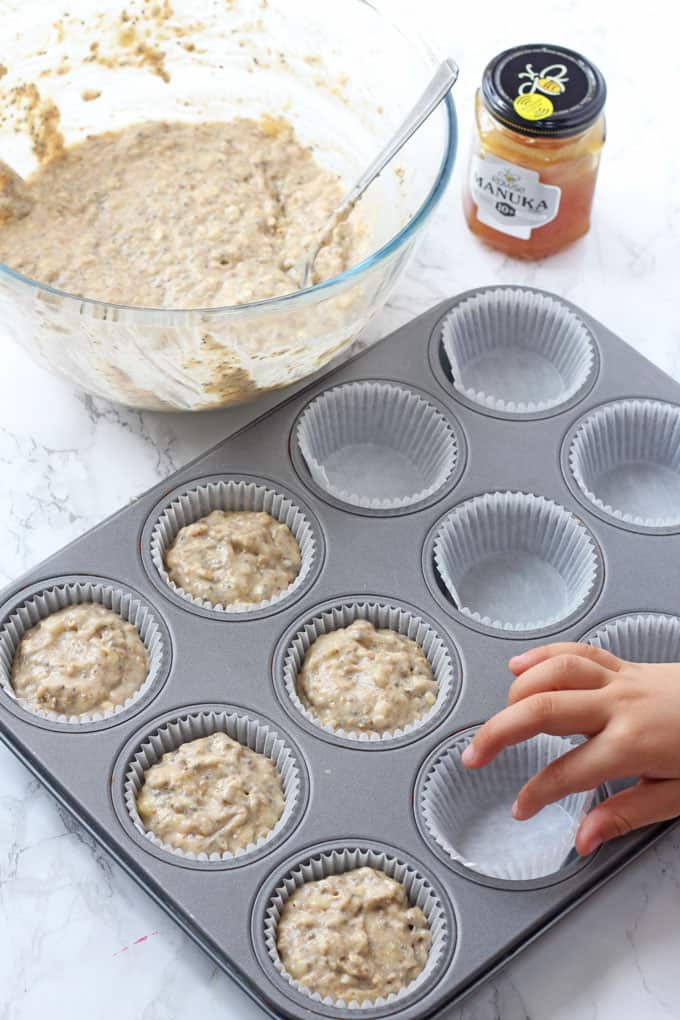 putting muffin mixture into muffin cases