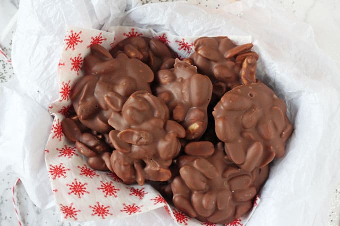Chocolate Peanut Clusters in a basket with a festive red and white snowflake napkin