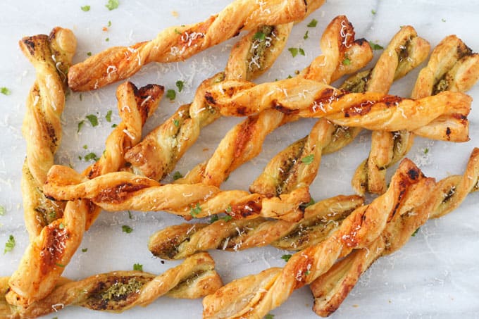 Pesto Parmesan Pastry Straws on a white marble surface