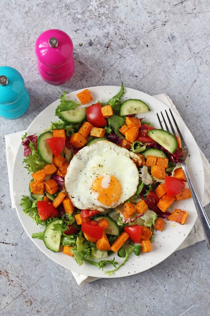 Winter Butternut Squash Salad served on a large round white plate with colorful salt and pepper grinders in the backgroud.