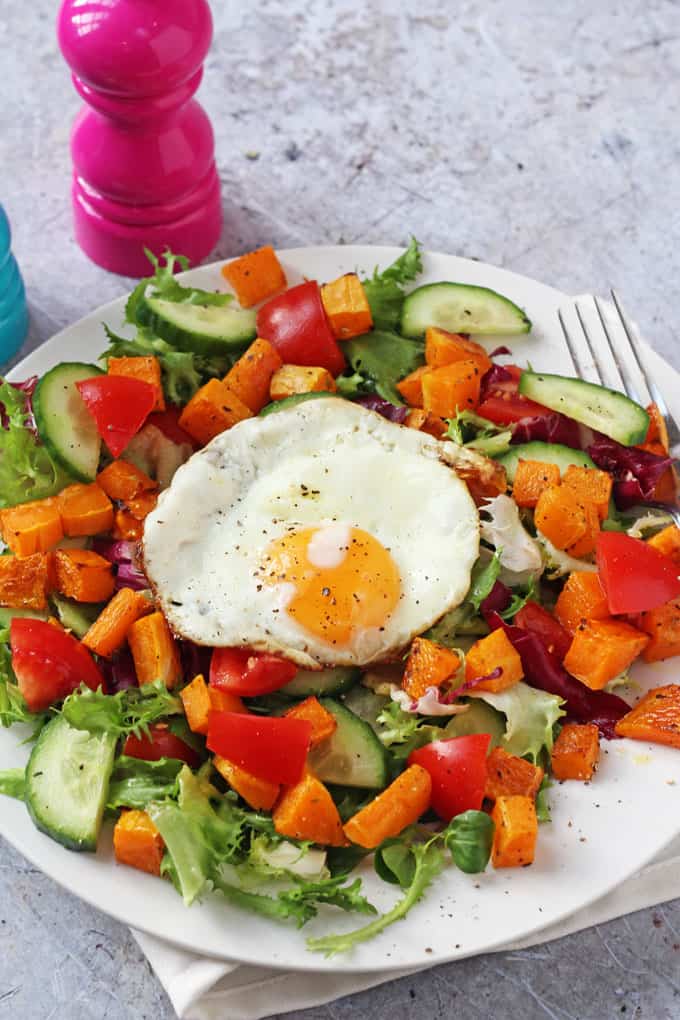 as close up shit of the winter salad topped with a fried egg and seasoned with salt and pepper