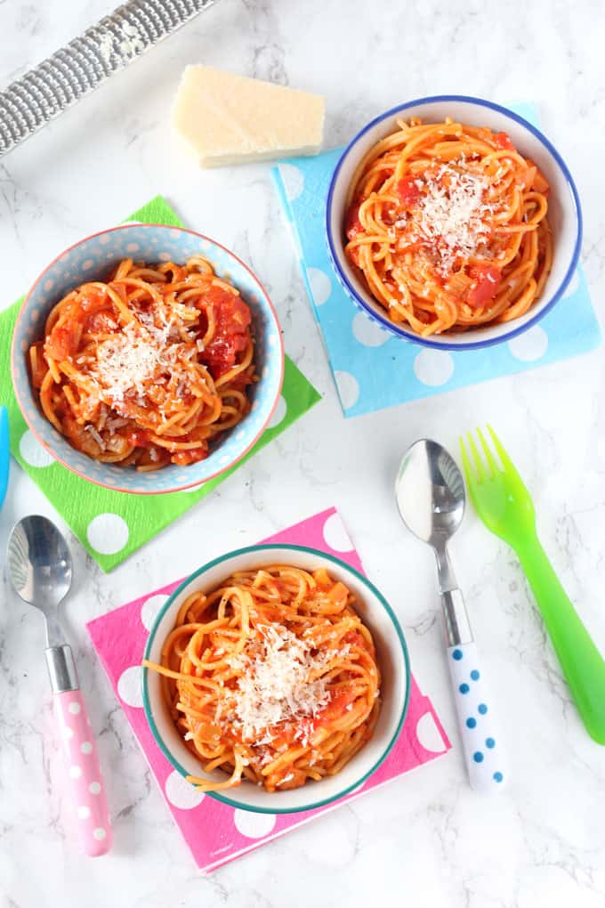 simple spaghetti & tomato sauce served in three small bowls on top of multi coloured polka dot napkins