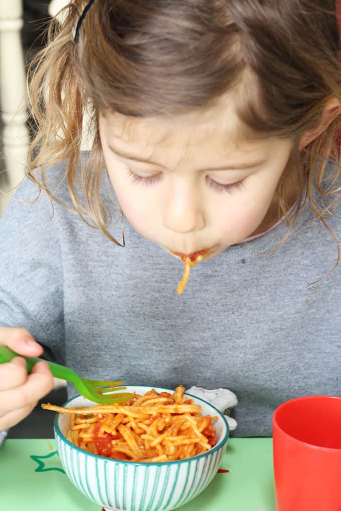 child eating a bowl of simple tomato spaghetti