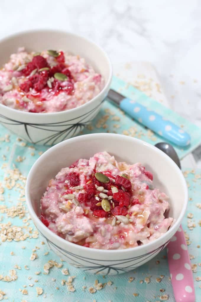 2 bowls of bircher muesli for kids shown sitting on top of a pale blue napkin