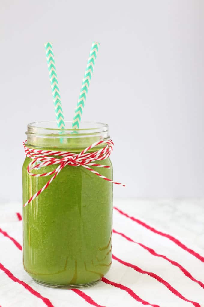 Tropical Kale Smoothie served in a jam jar with two colorful straws.