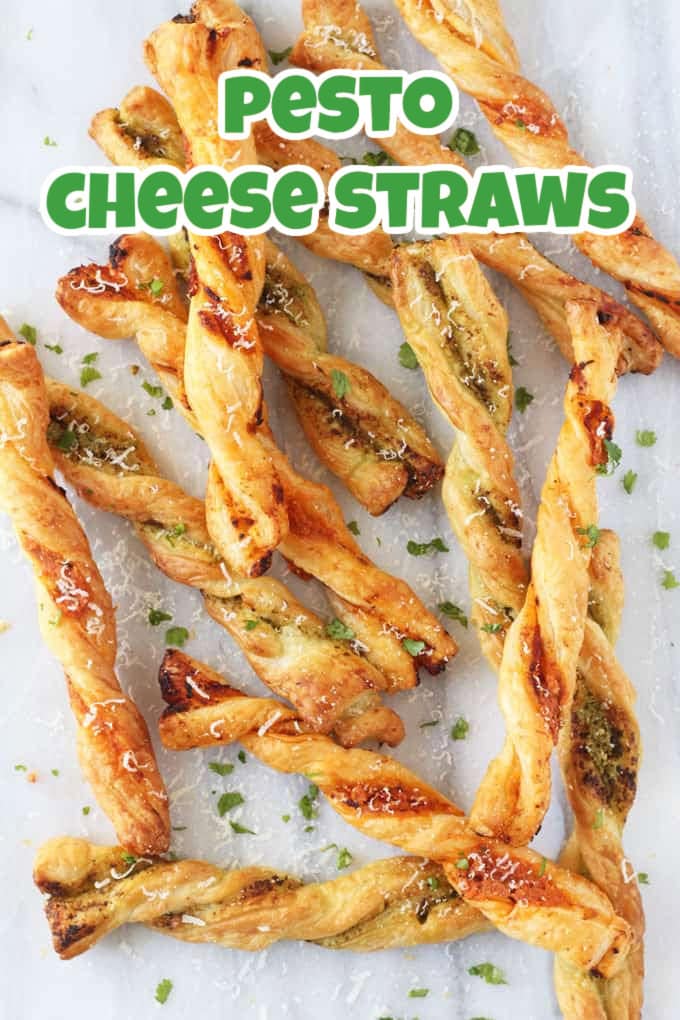 Cheesy Puff Pastry Straws garnished with basil and grated parmesan on a white marble chopping board.