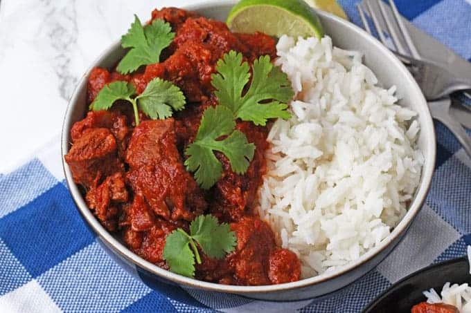 Slow Cooker Lamb Curry served in a bowl with white rice and garnished with coriander.