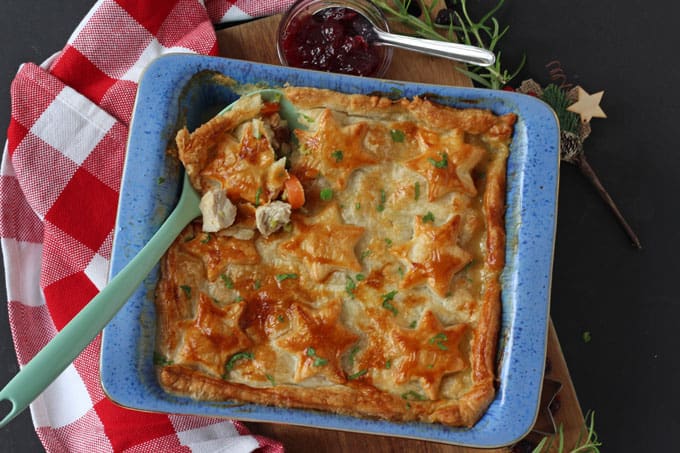 Turkey, cranberry and brie pie with a puff pastry sheet decorated with biscuit stars in a blue ovenproof dish