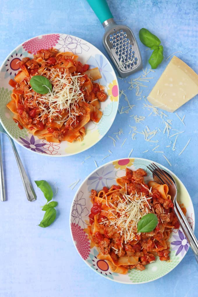 Easy sausage meat ragu,served on a pretty flower patterned plate, garnished with grated cheese and a basil leaf.