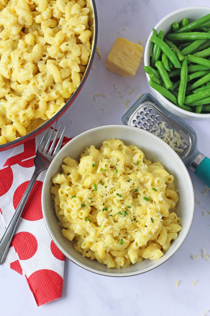 A bowl of Mac & Cheese with a side of green beans