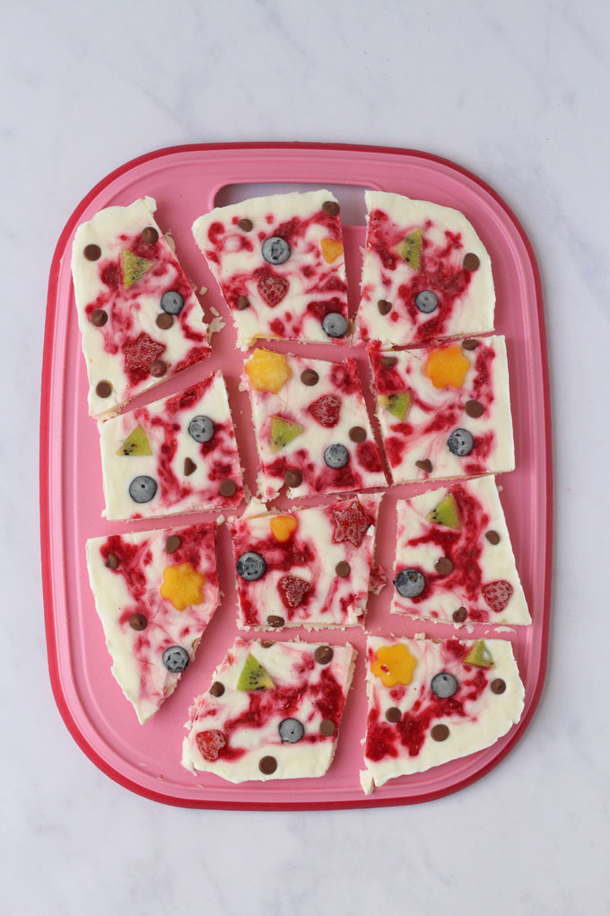 Frozen Yogurt Bark cut up on a pink board