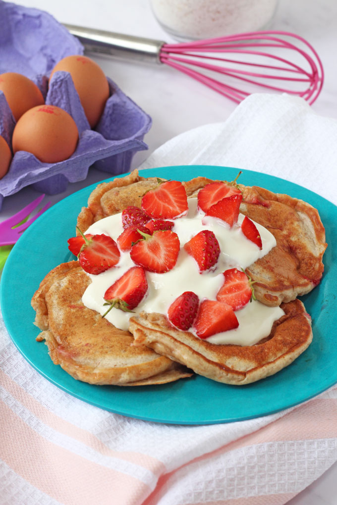 Strawberry Yogurt Pancakes topped with yogurt and strawberries on a blue plate