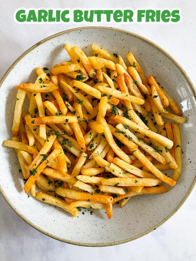 Garlic Butter fries served in a cream speckled ceramic bowl garnished with finely chopped parsley.
