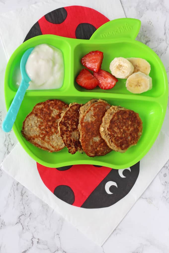 Banana & Oat Pancakes served on a divided plate with fruit and yogurt