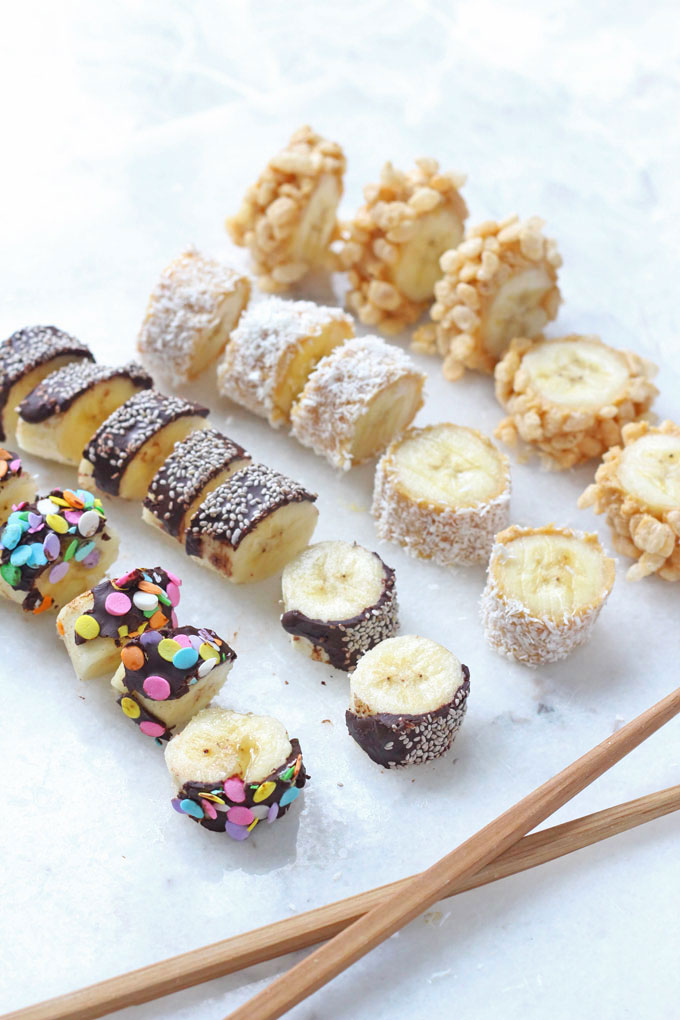 Banana Sushi served on a white marble chopping board. Decorated with various colourful toppings.