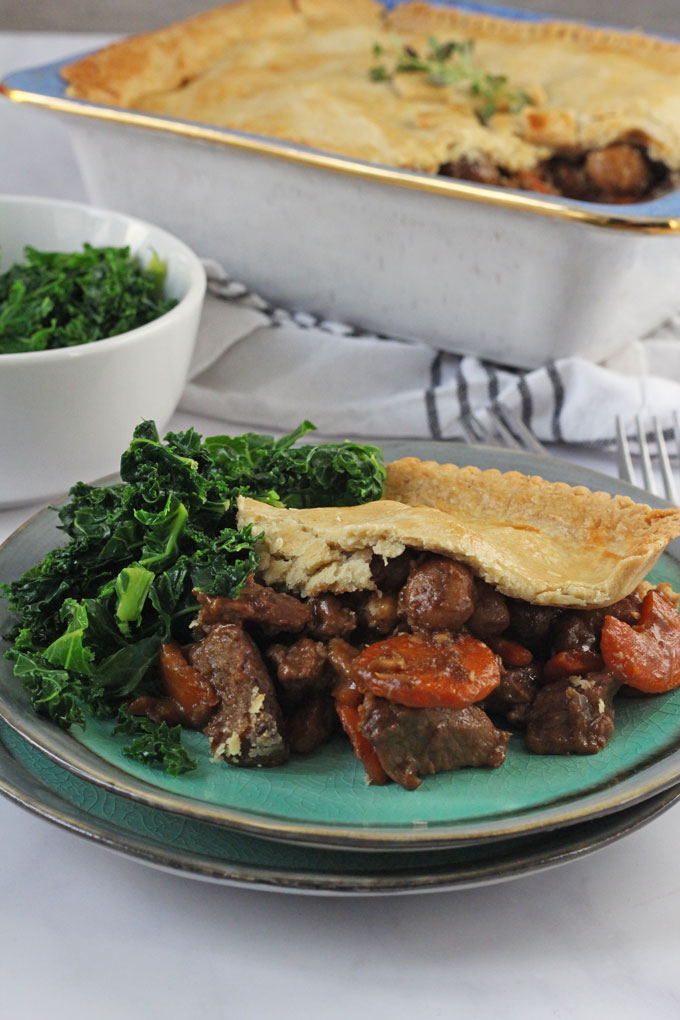 Winter Beef & Vegetable Pie served up with greens on a plate