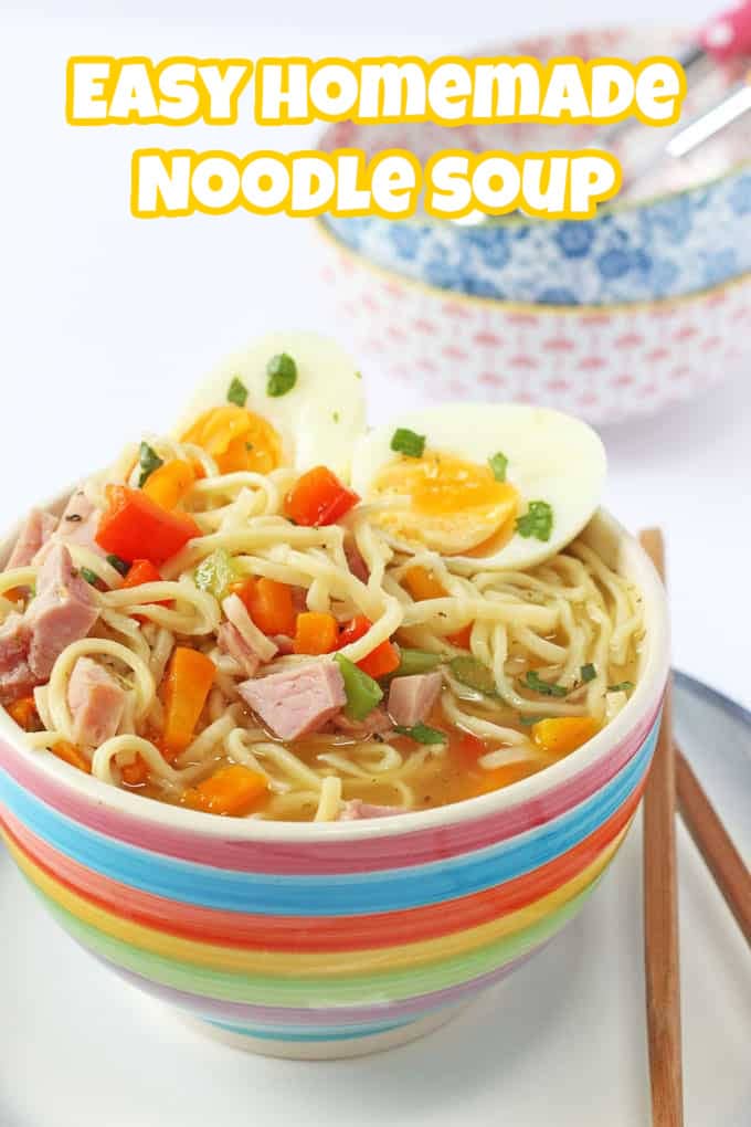 A bowl of ham and egg noodle soup served in a multicoloured striped bowl with a set of wooden chopsticks on the side.