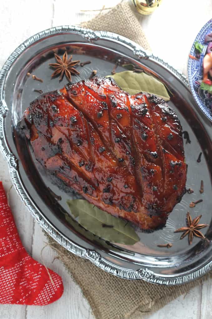 slow cooker christmas ham on a silver serving platter, garnished with star anise and bay leaves