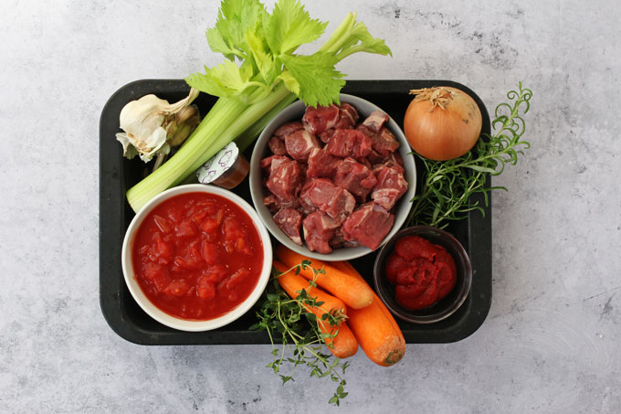 Ingredients for a Slow Cooked Lamb Ragu recipe on a black tray