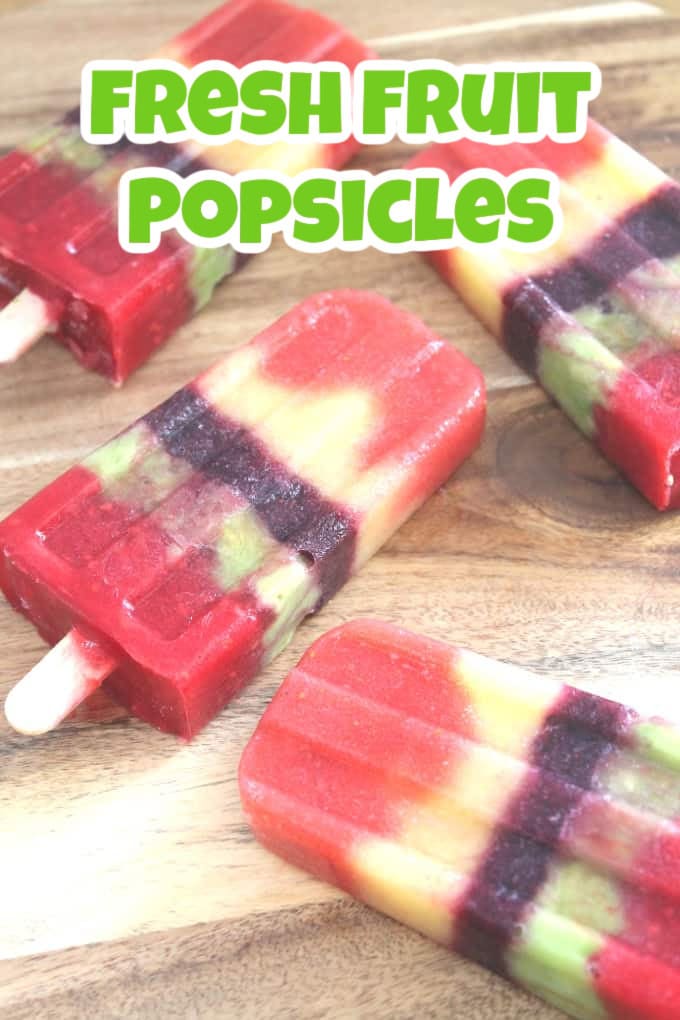 4 Homemade fruit popsicles laid flat on a wooden chopping board.