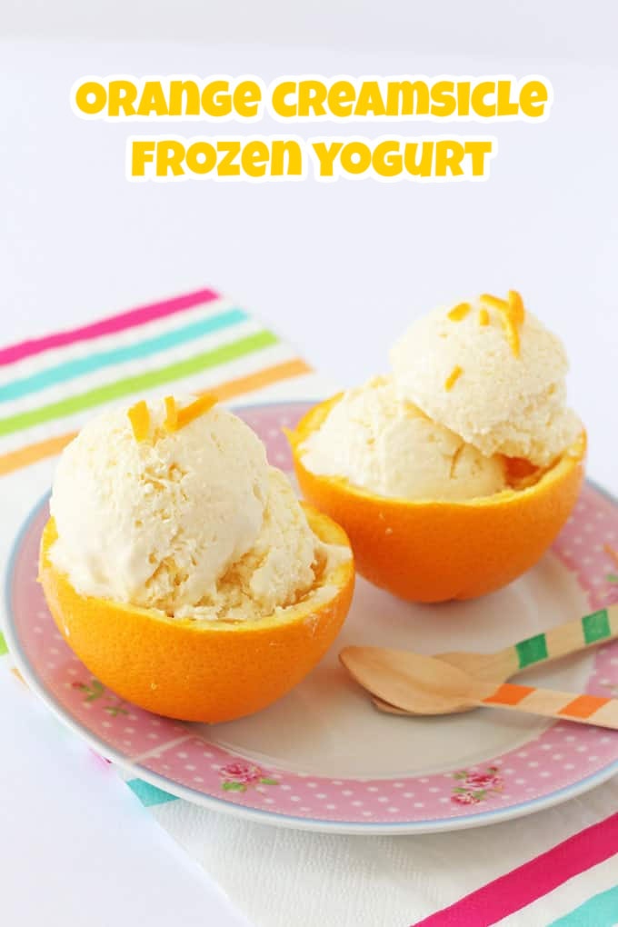 Orange Ice cream served in two fresh orange halves on as pink ditsy print plate and garnished with orange peel.