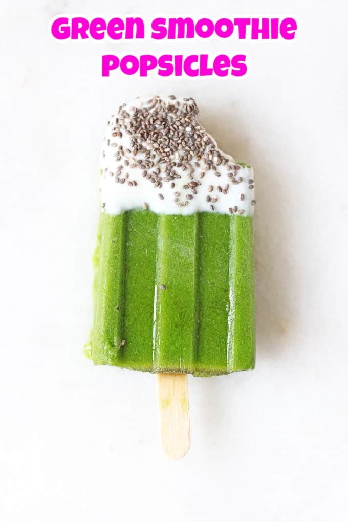 A green smoothie popsicle with a bite taken out of it laid on a white background.
