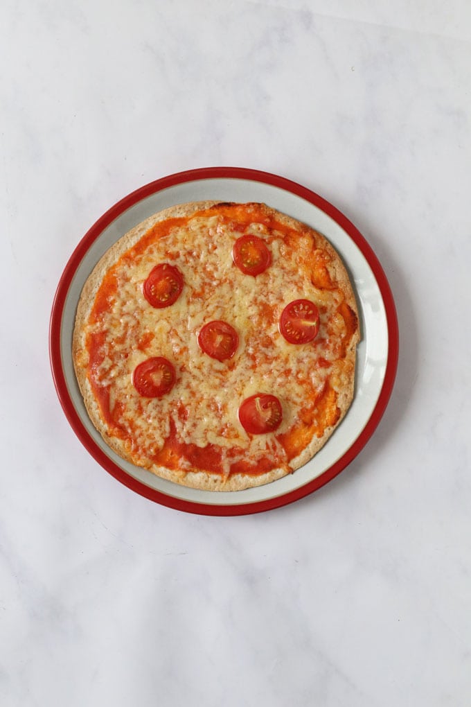 Hidden Veggie Tomato Sauce added to a tortilla wrap to make a pizza and topped with cheese and cherry tomatos