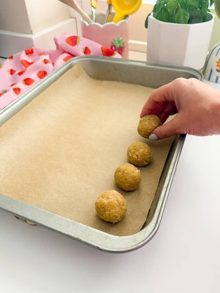 Chicken meatballs arrange on a baking tray on parchment paper.