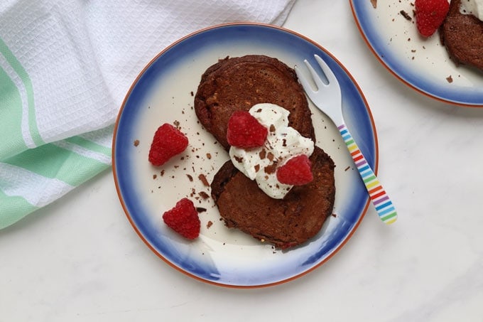 Easy Breakfast Recipes and Prep Ideas for Kids - Two plates of chocolate raspberry pancakes topped with a dollop of Greek yogurt and fresh raspberries