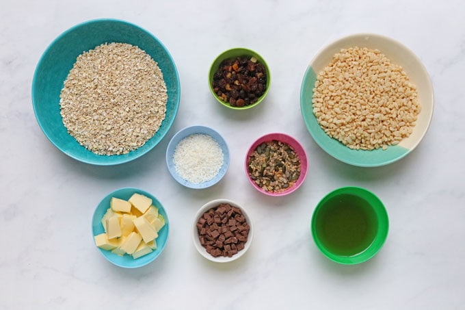 ingredients for the nut free granola bars measured out into various coloured bowls