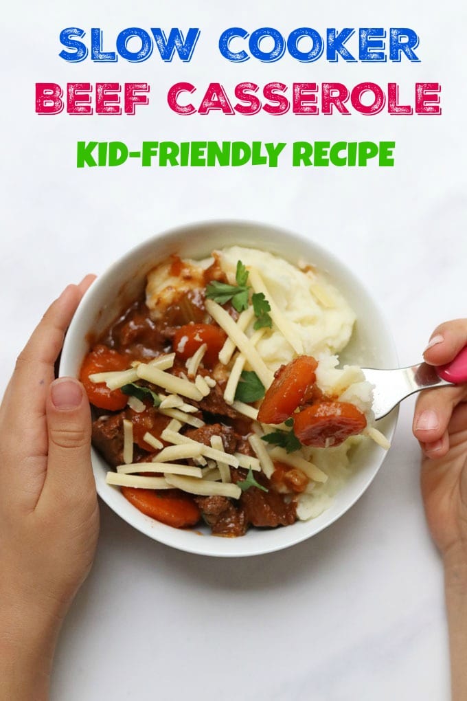 Slow Cooker Beef Casserole in a white bowl garnished with grated cheddar cheese and fresh parsley leaves