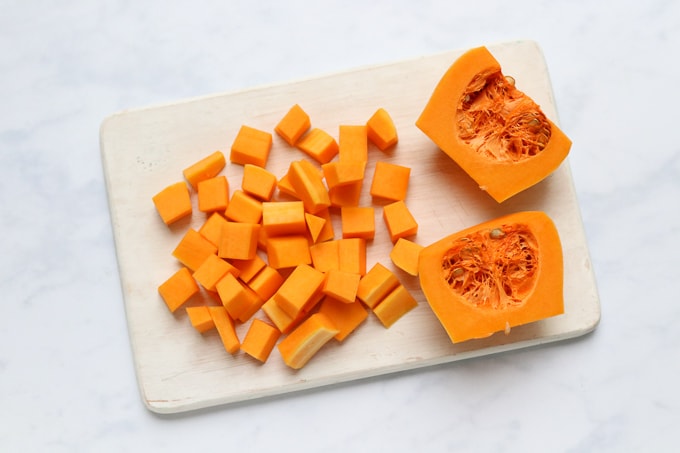 butternut squash peeled and chopped on a chopping board