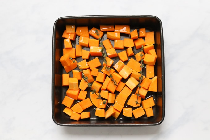 butternut squash in a roasting tin with olive oil and fresh thyme