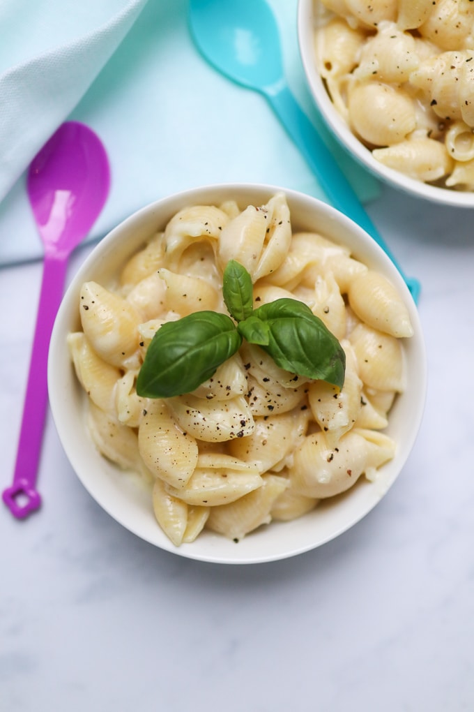 Cheesy Cauliflower Pasta in a white bowl garnished with fresh basil leaves and black pepper