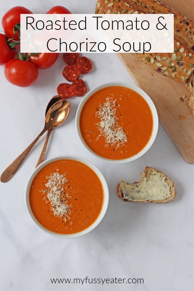 Two bowls of Roasted Tomato & Chorizo Soup with a seeded loaf, tomatoes on the vine and slices of chorizo next to them.