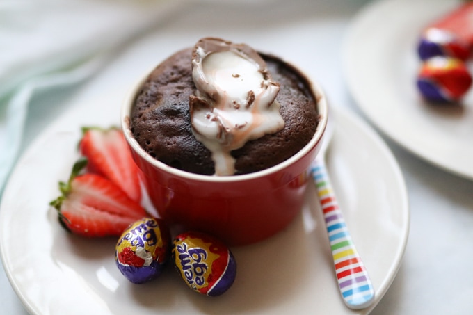Creme Egg Mug Cake on a plate with mini creme eggs and a strawberry