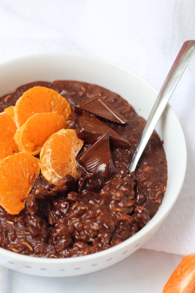 Chocolate Orange Porridge served in a white bowl, topped with clementine segments and squares of chocolate.