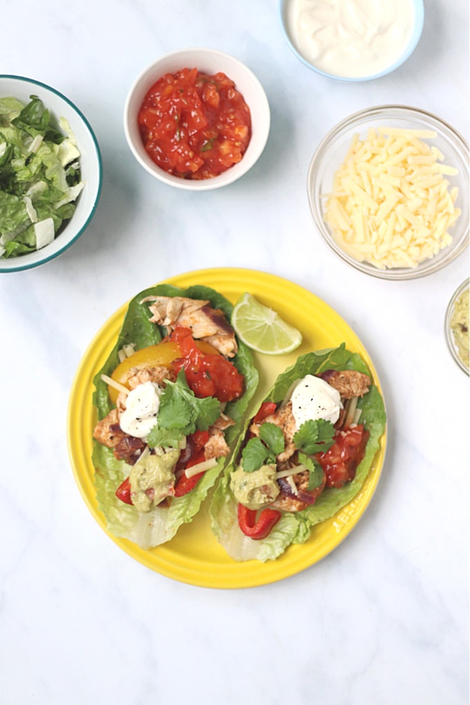 healthy chicken fajitas served on a bright yellow round dinner plate and garnished with a slice of lime.
