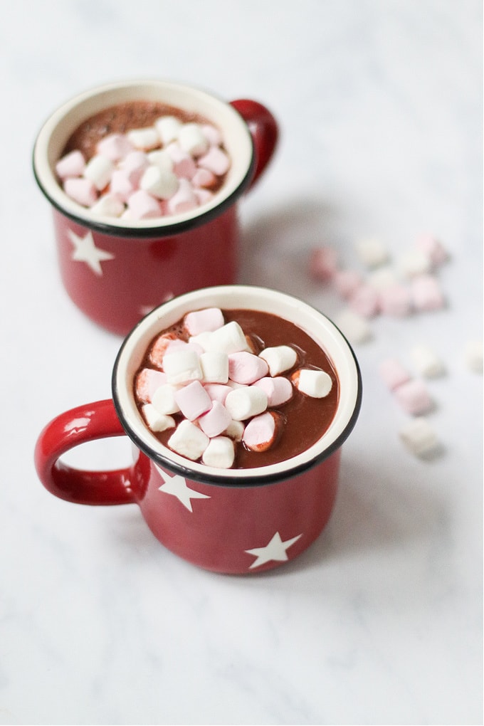 Coconut Hot Chocolate served in festive red cups with white stars, garnished with mini marshmallows.