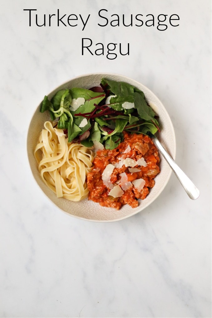 turkey sausage ragu served in a white bowl with a portion of pasta and a small side salad