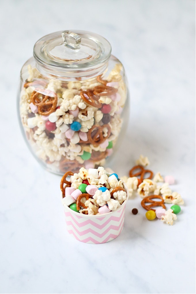 This Popcorn Trail Mix makes a delicious sweet treat for just 110 calories per portion. Perfect to make in bulk for grab-and-go snacks all week long. served in a large glass jar with some in a cute muffin case ready to eat.