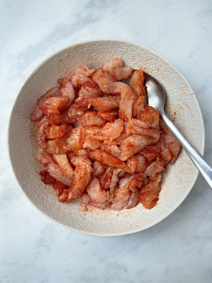 strips of turkey steak in a bowl mixed with paprika, garlic and onion powder 