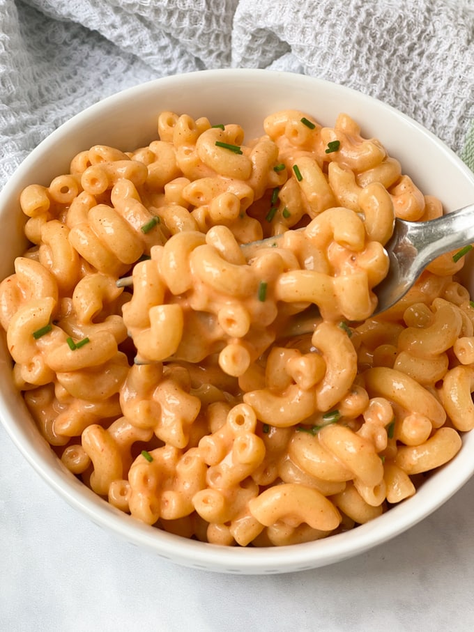 close up of buffalo mac & cheese on a fork in a white bowl