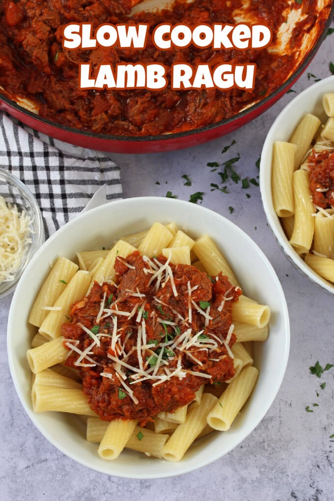 Slow Cooked Lamb Ragu served in a white bowl with cooked white pasta and a sprinkling of finely grated cheese and freshly chopped basil.