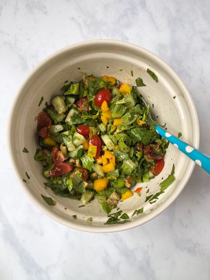 ingredients mixed together in the bowl with salad dressing