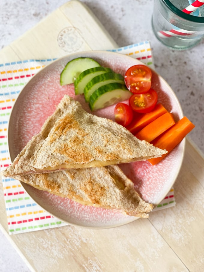 the finished toaster toastie served on a pink plate with crudites